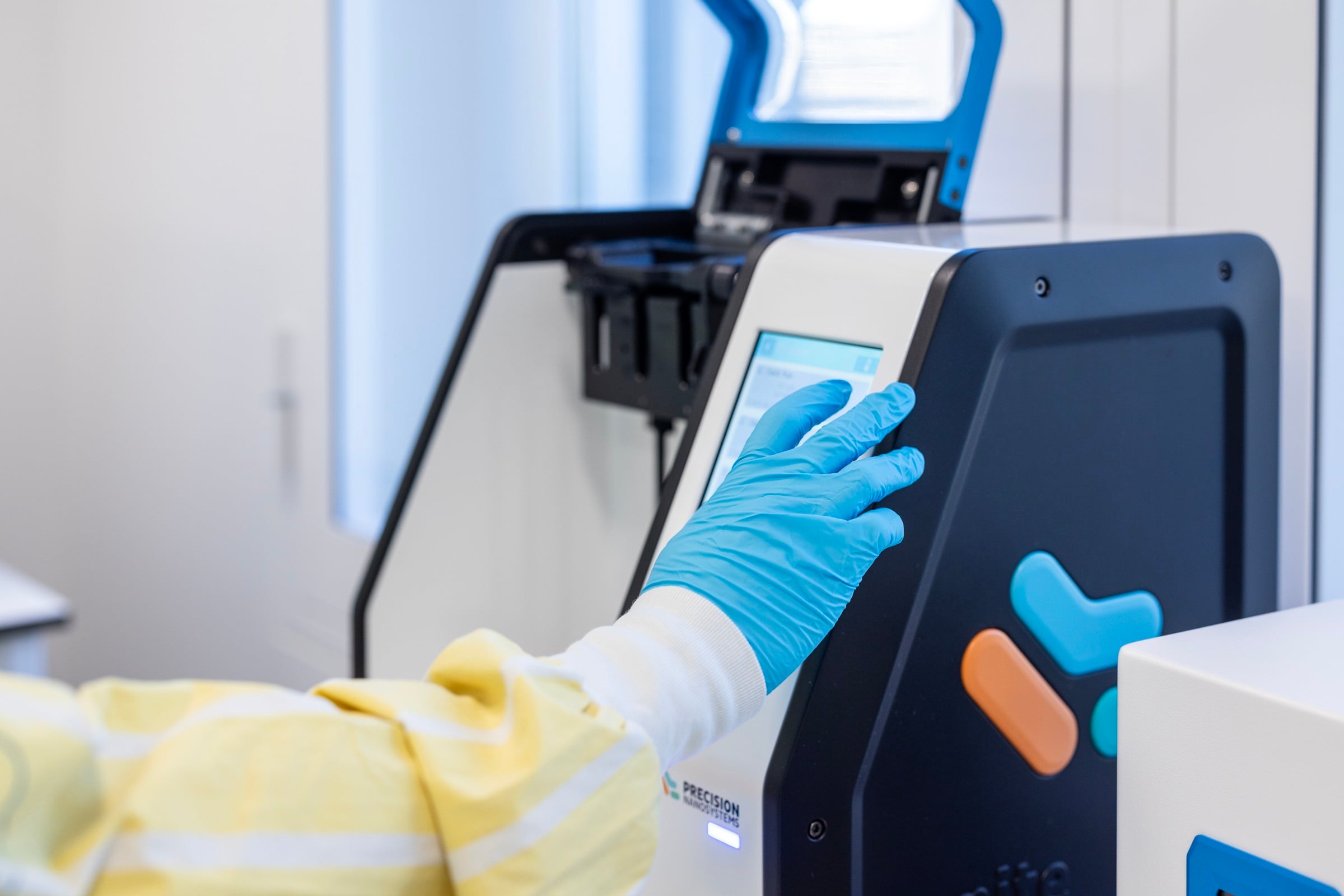 A person in blue gloves is operating a machine.