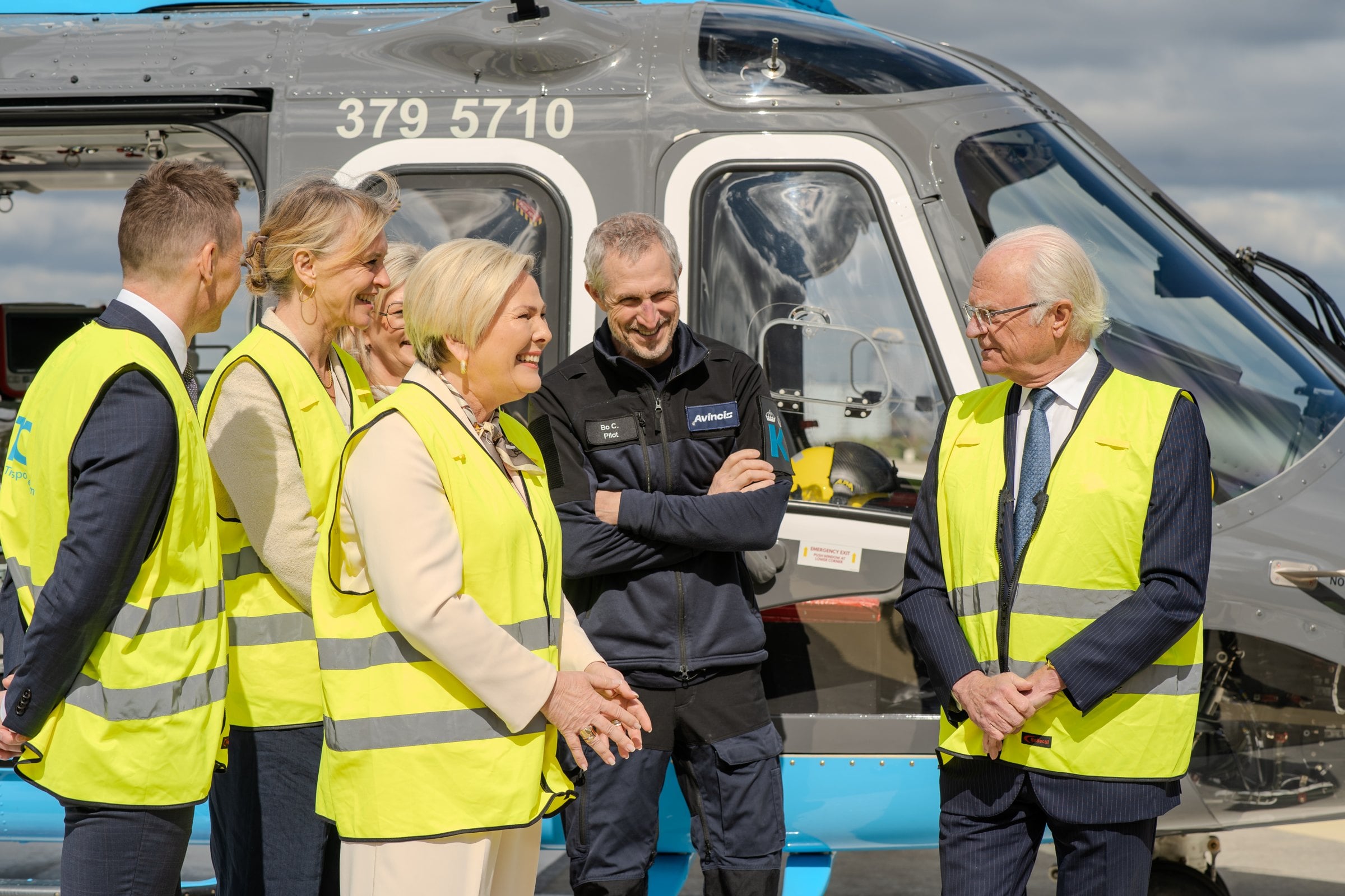 A group of people standing in front of a helicopter.