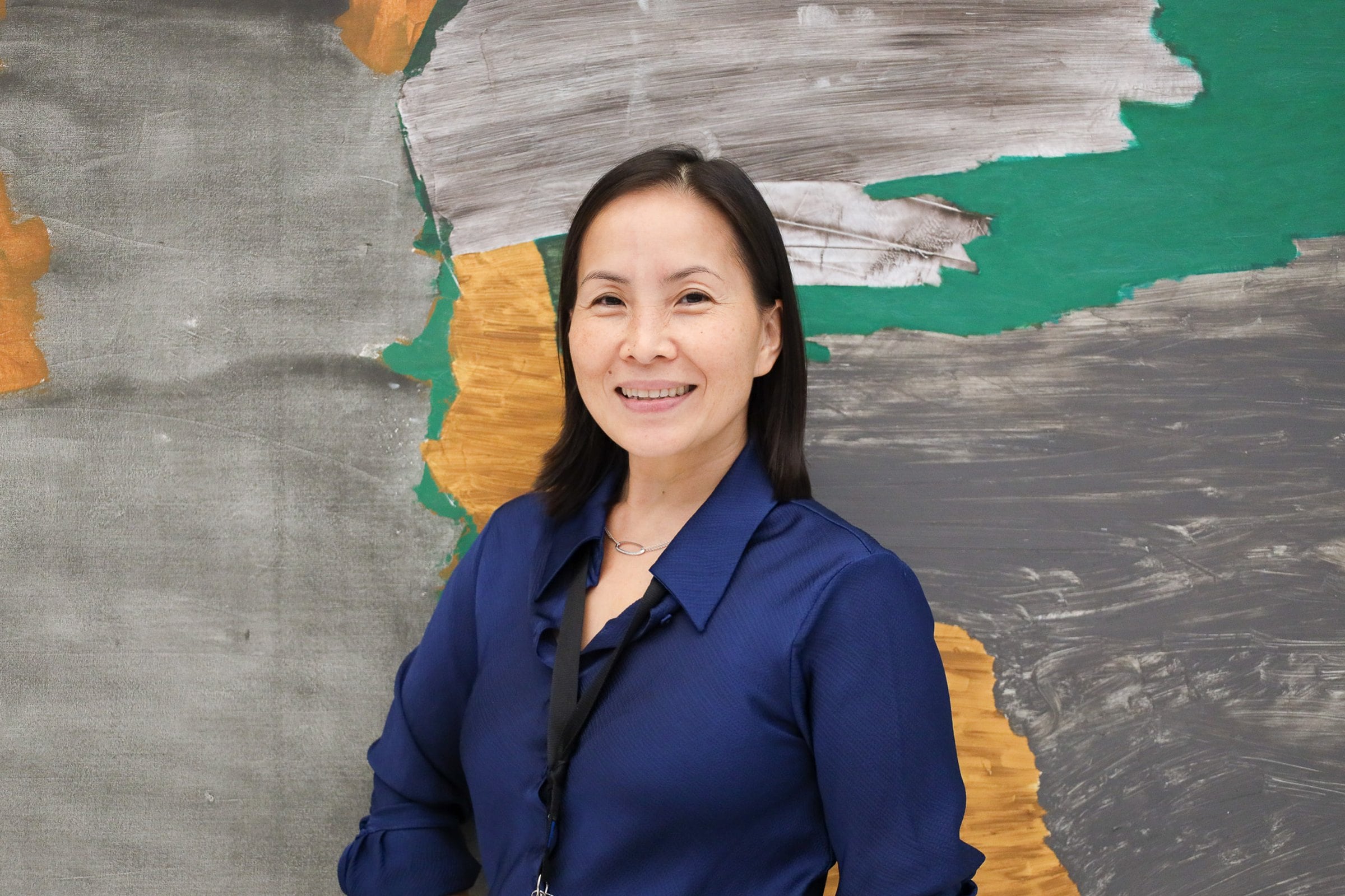 Woman with black hair and blue shirt looking into the camera smiling